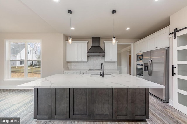 kitchen featuring appliances with stainless steel finishes, custom exhaust hood, a sink, white cabinets, and tasteful backsplash