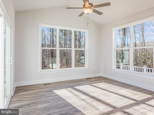 spare room with plenty of natural light, baseboards, wood finished floors, lofted ceiling, and a ceiling fan