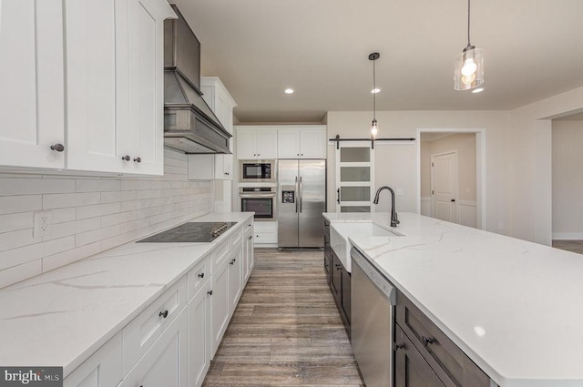 kitchen featuring stainless steel appliances, wood finished floors, a sink, backsplash, and white cabinets