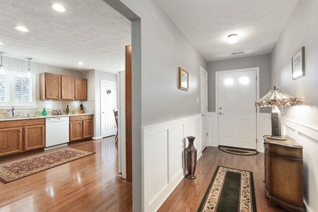 521 Hickory Grove Cir, Harrisonburg, VA 22801 - doorway to outside featuring a textured ceiling, dark wood-style flooring, a sink, a wainscoted wall, and a decorative wall