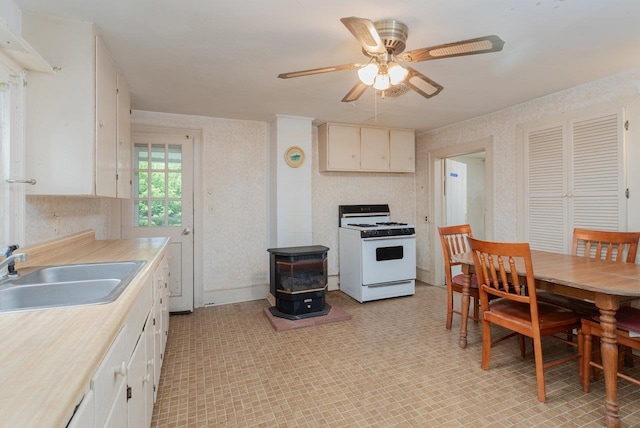 56 Grindstone Rd, Bridgewater, VA 22812 - kitchen featuring white range with gas stovetop, a sink, a wood stove, ceiling fan, and light countertops