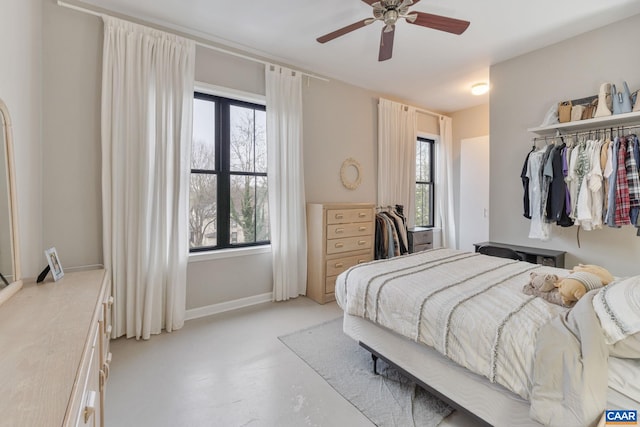 bedroom with multiple windows, baseboards, concrete flooring, and a ceiling fan