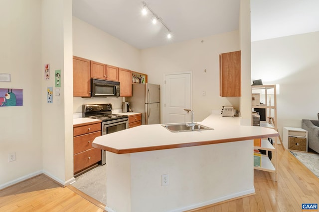 kitchen featuring freestanding refrigerator, a sink, stainless steel electric stove, black microwave, and light wood-type flooring