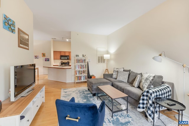 living area with track lighting, light wood-type flooring, and visible vents