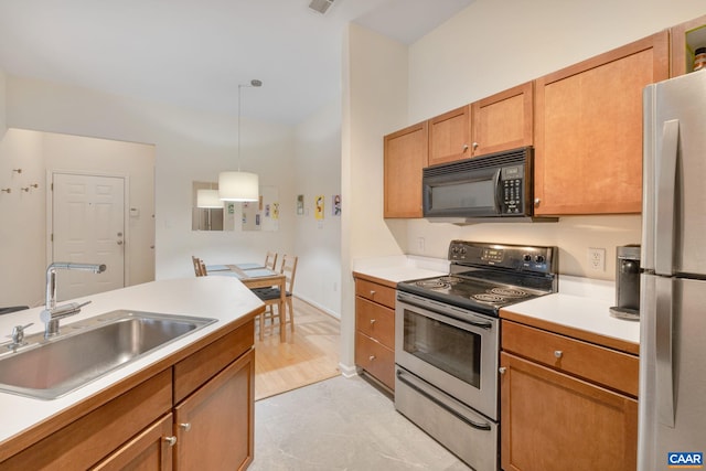 kitchen with light countertops, stainless steel appliances, a sink, and decorative light fixtures