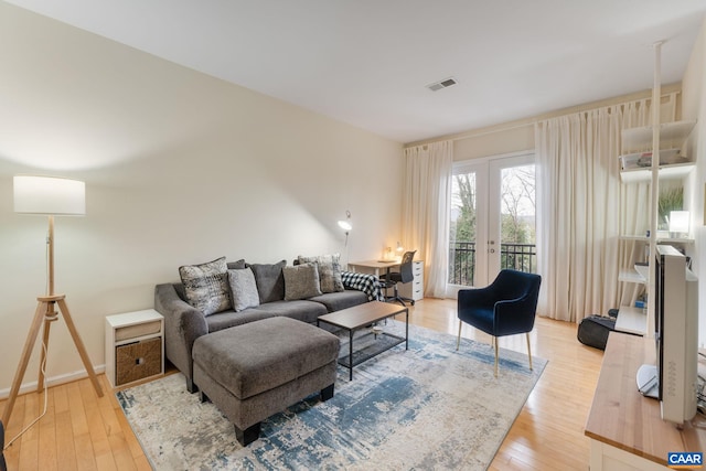 living area with light wood-style flooring, french doors, and visible vents