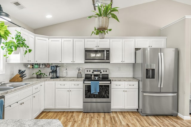 96 Lofty Cir, Stuarts Draft, VA 24477 - kitchen featuring stainless steel appliances, vaulted ceiling, white cabinets, light wood-type flooring, and tasteful backsplash