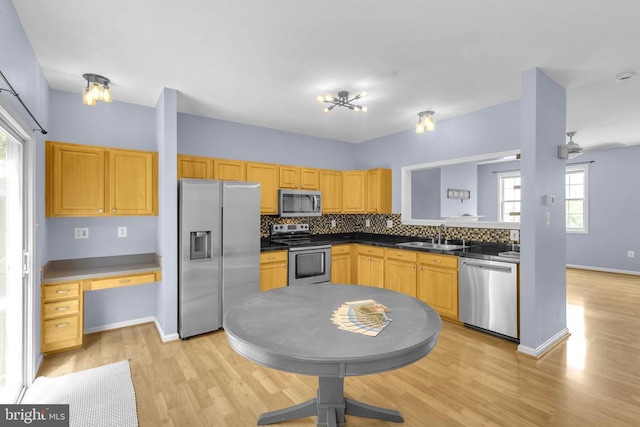 55 Sire Way, Warrenton, VA 20186 - kitchen with appliances with stainless steel finishes, light wood-type flooring, decorative backsplash, dark countertops, and built in desk