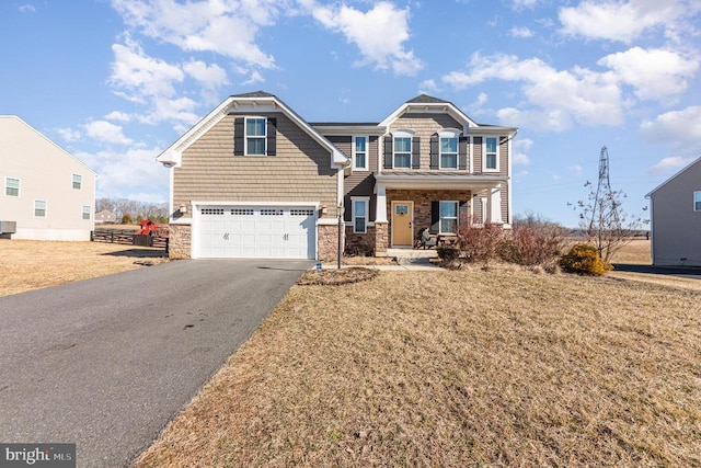 craftsman-style home featuring a garage, a front yard, stone siding, and driveway