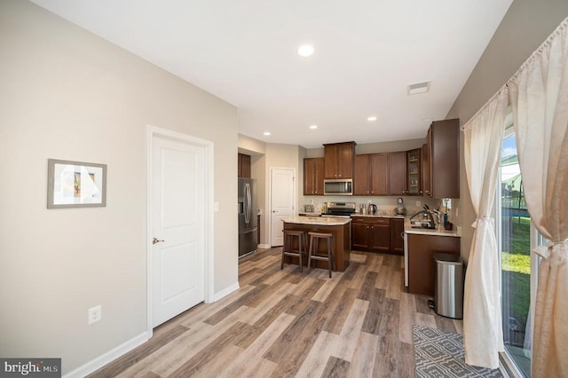 9528 Fall Haven Rd, Fredericksburg, VA 22407 - kitchen featuring appliances with stainless steel finishes, a kitchen island, light countertops, light wood-type flooring, and a kitchen bar