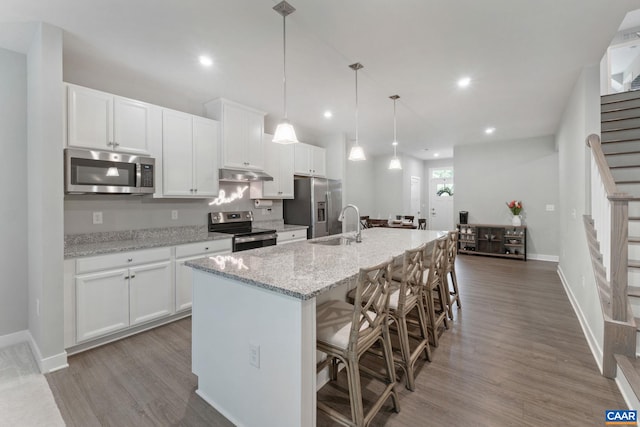 712 Empire St, Charlottesville, VA 22901 - kitchen with appliances with stainless steel finishes, under cabinet range hood, a center island with sink, wood finished floors, and white cabinets