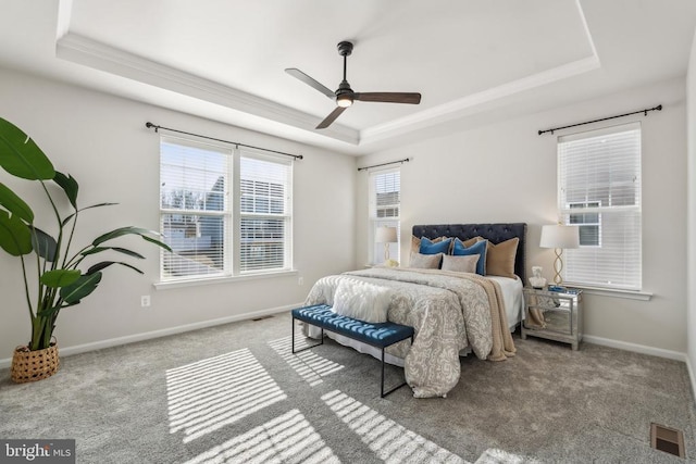 bedroom featuring a tray ceiling, carpet, baseboards, crown molding, and a ceiling fan