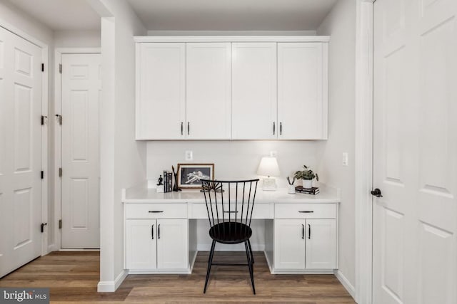 home office featuring built in desk, wood finished floors, and baseboards