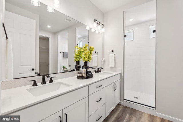bathroom featuring a stall shower, wood finished floors, double vanity, recessed lighting, and plenty of natural light