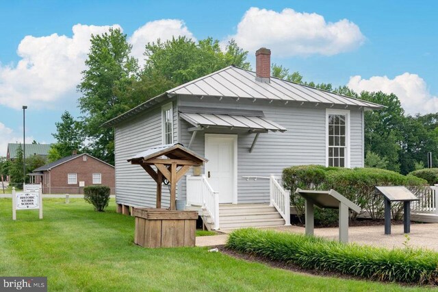 view of front of home featuring a standing seam roof, a front lawn, a chimney, and metal roof