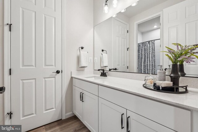 full bathroom with vanity, wood finished floors, and baseboards