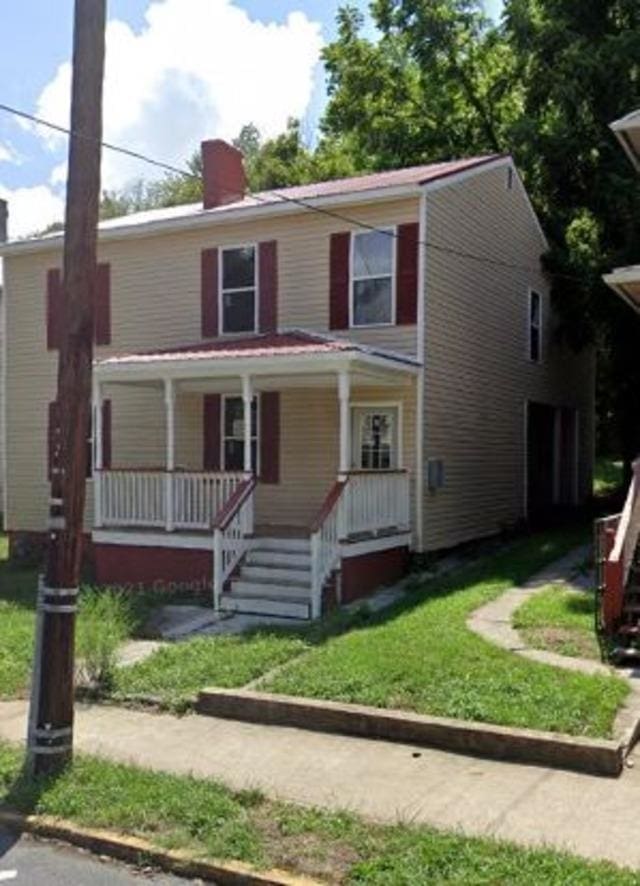 view of front of house with a front lawn, a porch, and a chimney