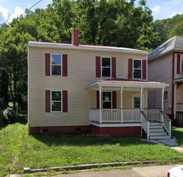 colonial inspired home with a chimney, a porch, a front lawn, and crawl space