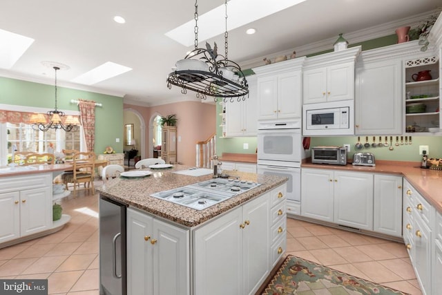 11306 Stonewall Jackson Dr, Spotsylvania, VA 22551 - kitchen featuring a chandelier, white appliances, a skylight, light tile patterned flooring, and white cabinetry