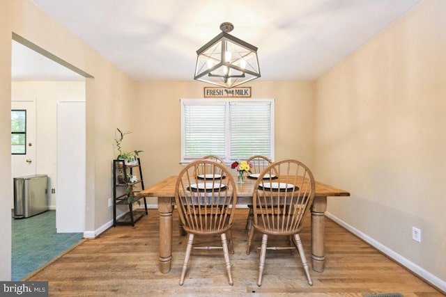  - dining space featuring baseboards, wood finished floors, and a chandelier