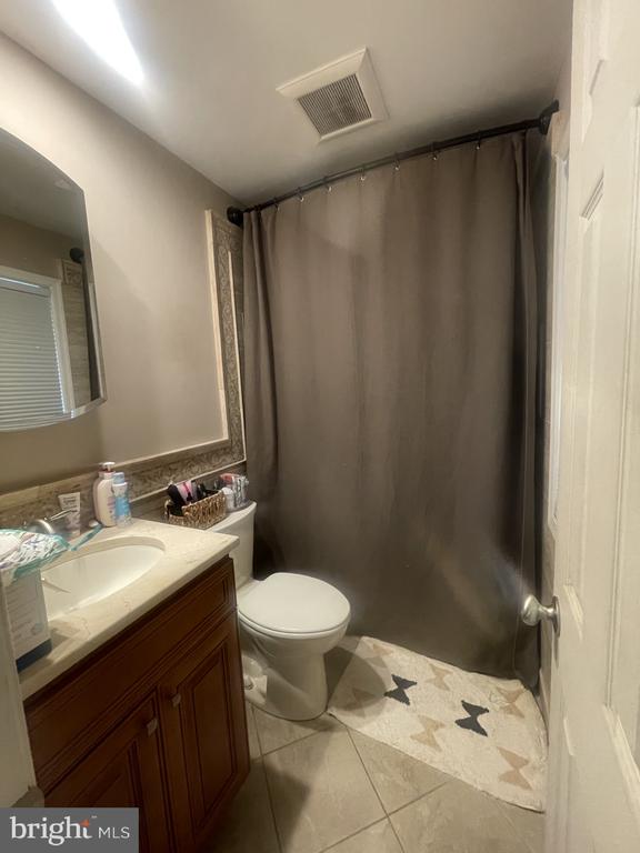 full bath with tile patterned floors, vanity, toilet, and curtained shower