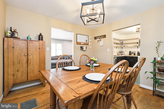  - dining area with a chandelier, light wood-style flooring, and baseboards