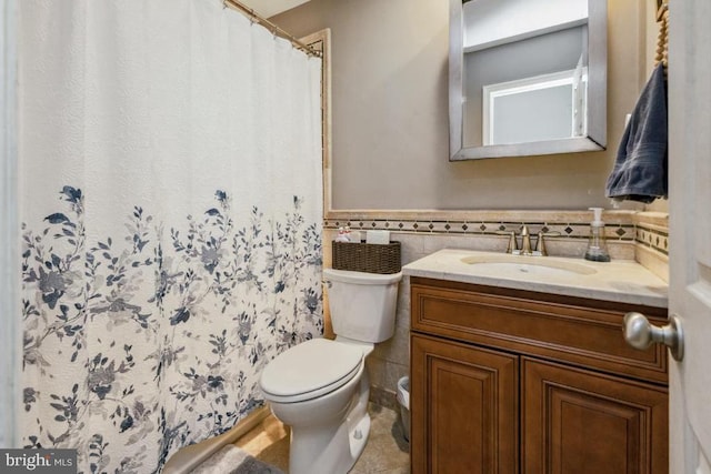  - full bath featuring toilet, vanity, a wainscoted wall, tile walls, and curtained shower