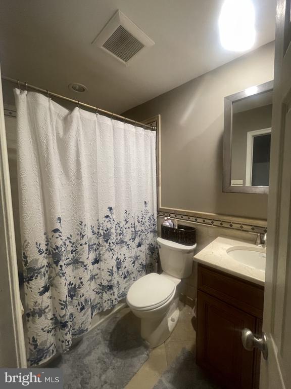 bathroom featuring vanity, toilet, tile patterned flooring, and a shower with shower curtain
