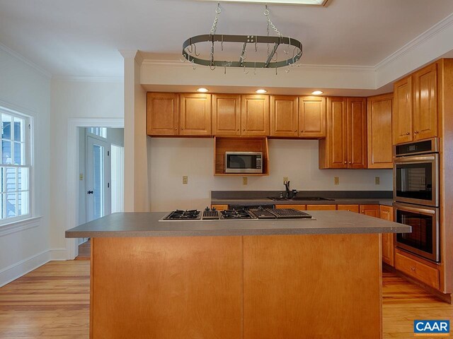 kitchen with sink, crown molding, light hardwood / wood-style flooring, appliances with stainless steel finishes, and a center island