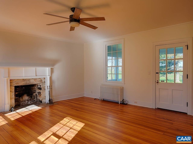 unfurnished living room featuring crown molding, radiator, a fireplace, and light hardwood / wood-style flooring