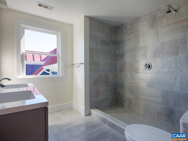 bathroom featuring vanity, tiled shower, and toilet