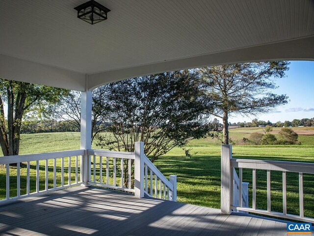 wooden deck with a rural view and a lawn