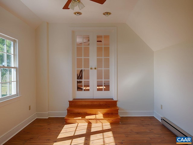 interior space with hardwood / wood-style floors, lofted ceiling, a baseboard heating unit, ceiling fan, and french doors