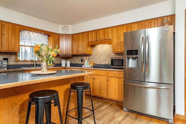 17962 Old Barn Ln, Elkton, VA 22827 - kitchen featuring stainless steel appliances, brown cabinets, a breakfast bar, backsplash, and light wood-style floors