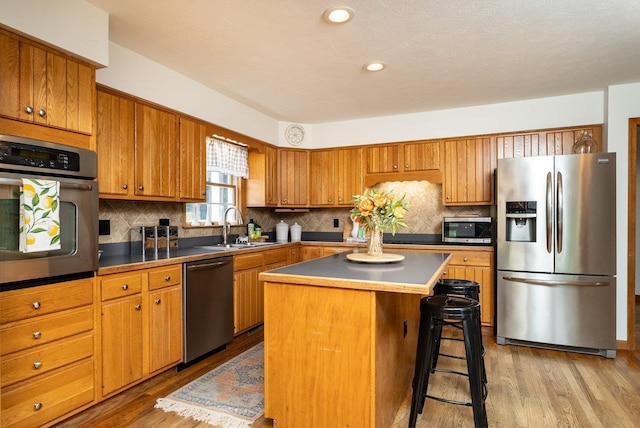 17962 Old Barn Ln, Elkton, VA 22827 - kitchen with stainless steel appliances, brown cabinetry, light wood-style floors, a breakfast bar, and recessed lighting