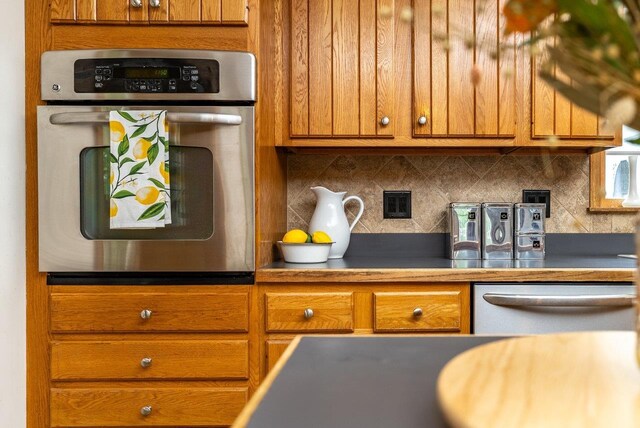 17962 Old Barn Ln, Elkton, VA 22827 - kitchen with appliances with stainless steel finishes, brown cabinets, decorative backsplash, and dark countertops