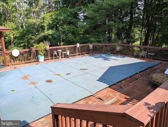  - view of pool with a wooden deck and view of wooded area