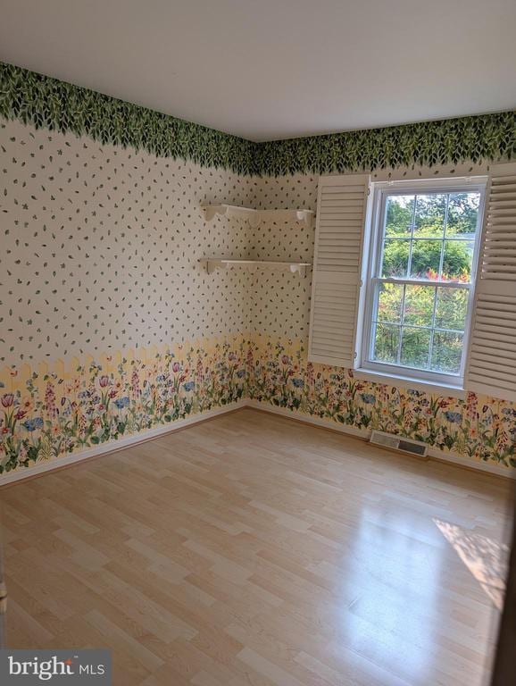  - empty room with baseboards, wallpapered walls, and light wood-style flooring