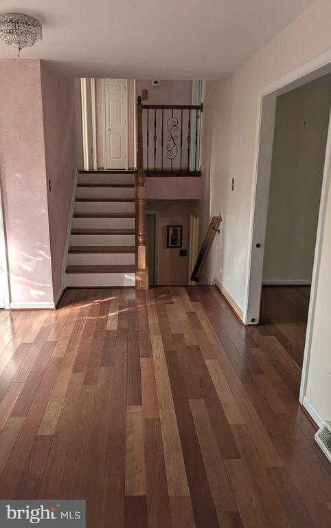 - unfurnished living room featuring wood finished floors, stairway, and baseboards
