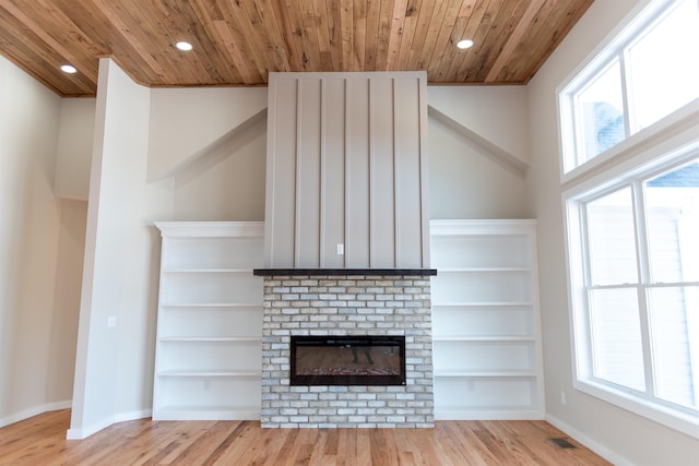 unfurnished living room with wood ceiling, a fireplace, built in features, and light wood-type flooring