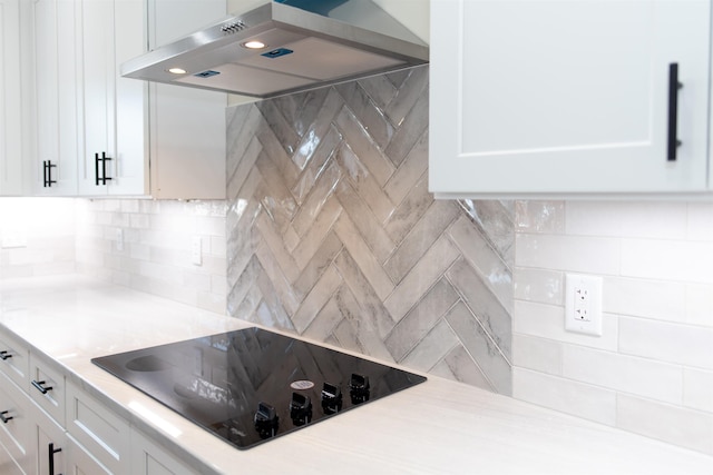 kitchen with tasteful backsplash, white cabinetry, black electric cooktop, and range hood