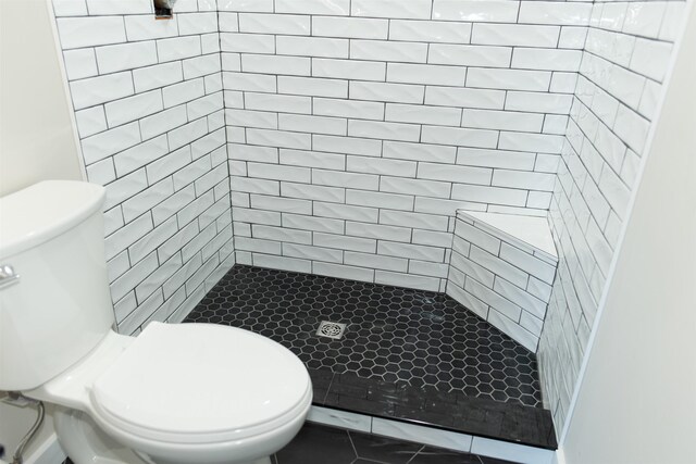 bathroom featuring tile patterned floors, toilet, and tiled shower