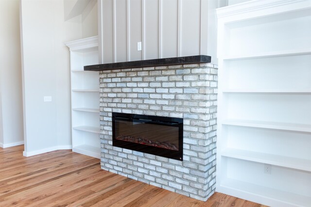 room details with wood-type flooring, a fireplace, and built in shelves