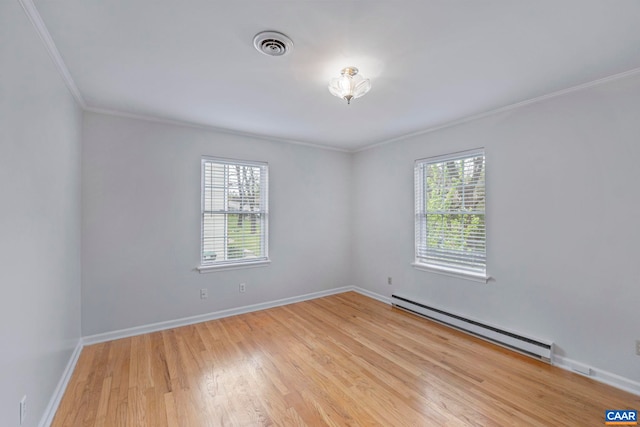 empty room featuring baseboard heating, healthy amount of natural light, ornamental molding, light wood-style flooring, and baseboards