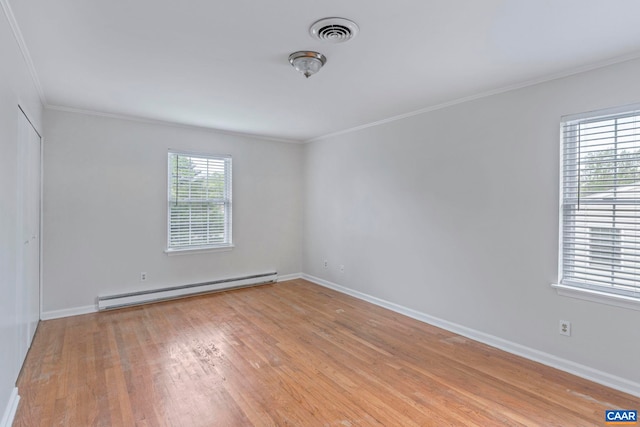 empty room featuring baseboard heating, ornamental molding, light wood-style flooring, and baseboards