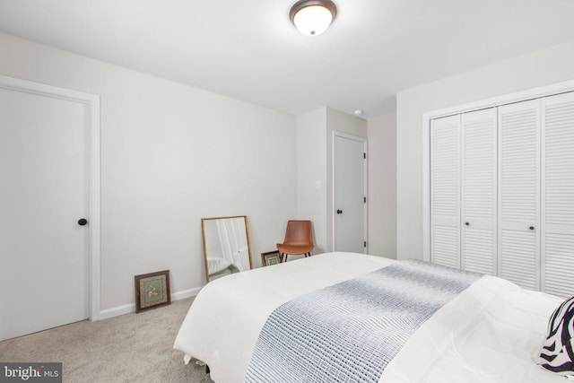 carpeted bedroom with a closet and baseboards