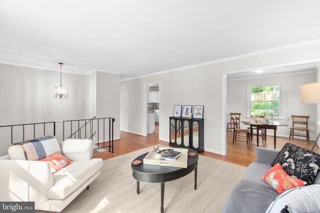 living area featuring crown molding, wood finished floors, baseboards, and a chandelier