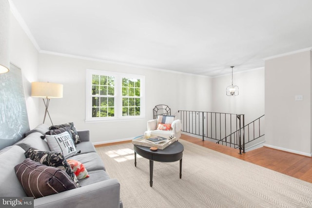 living area featuring wood finished floors, ornamental molding, a chandelier, and baseboards