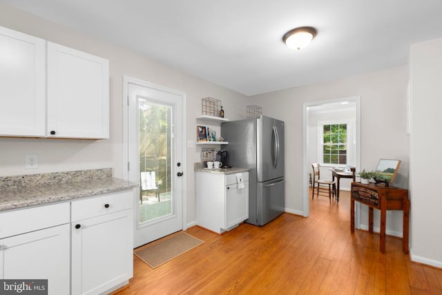 kitchen with freestanding refrigerator, white cabinetry, light wood-style floors, open shelves, and baseboards