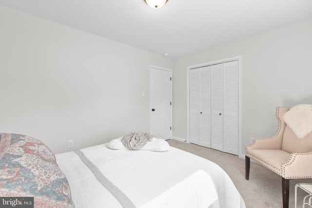 carpeted bedroom with a closet and baseboards